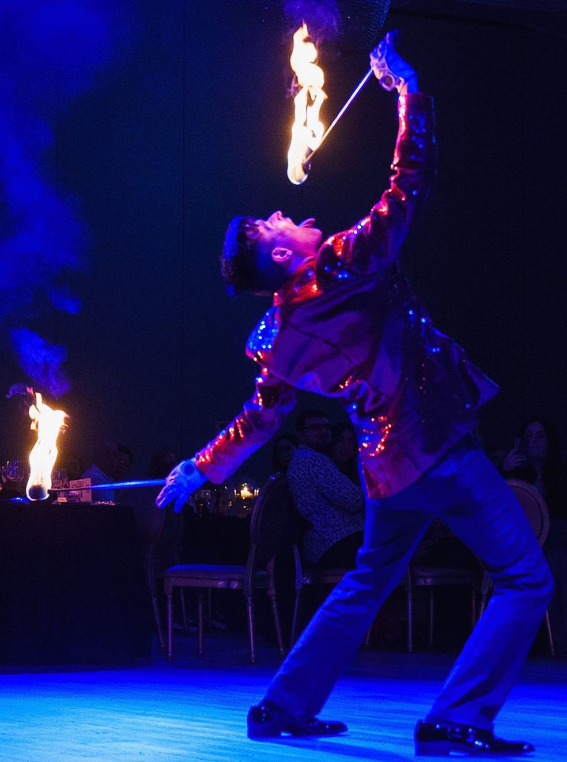 FireGuy eating fire at a fancy dress banquet.