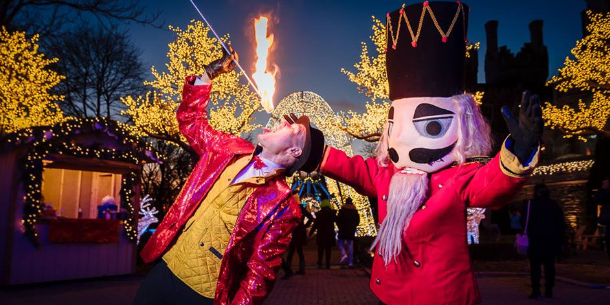 FireGuy is eating some fire next to the Nut Cracker at a Christmas show.
