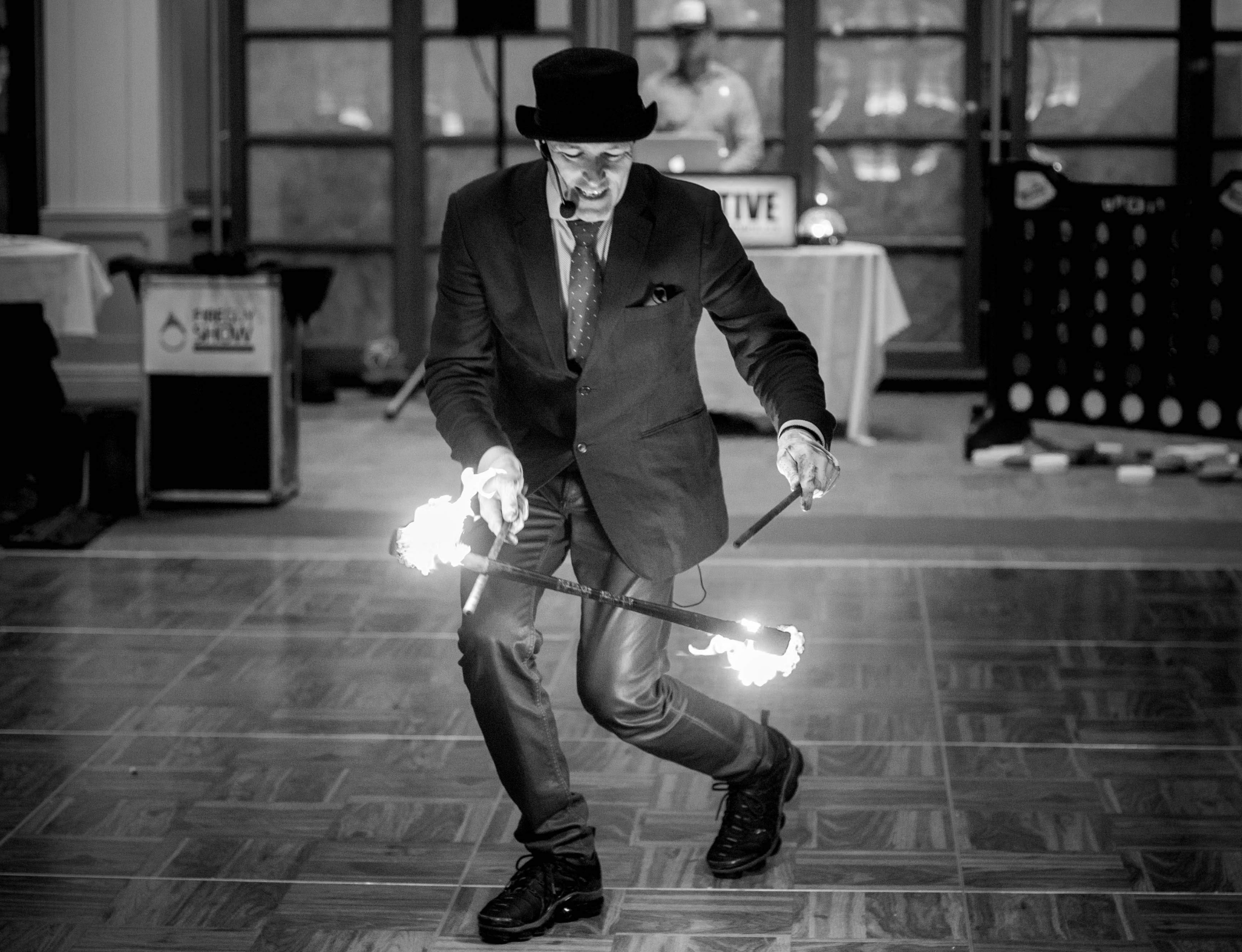 FireGuy dressed up fancy, juggling a fire baton inside.